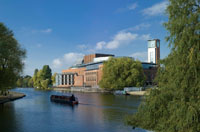 A theatre next to a big river, a barge sails past.