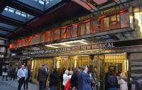 people standing casullay outside the Savoy Theatre in London