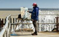 Photo of a man painting by the sea