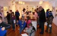 A photo of children in a gallery with pictures on the wall