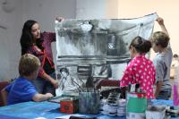 Photo of teacher with children holding up large drawing