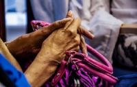 A close up photo of a persons' hands resting on a pink handbag