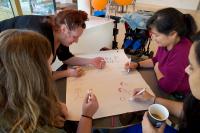 Group of women drawing stickmen around a table