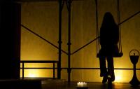 Photo of a performer on stage, sitting on a swing