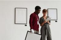 Two people in a gallery looking at a tablet