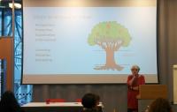 Photo of Ruth Soetendorp presenting in front of an image of a tree