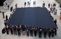 Photo of people holding a large black square of fabric in the Turbine Hall