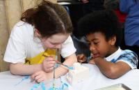 A photo of a boy and a girl painting a small item