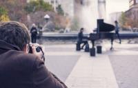 A photo of a man photographing a street piano player