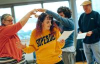 A photo of people dancing and a woman reading from a sheet