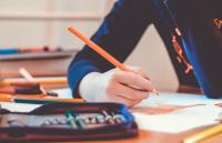 A pupil at a desk holidng a pencil