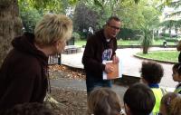 Photo of a man and woman leading outdoor workshop about trees to young children