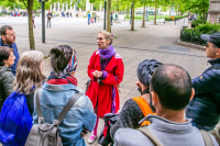 a tour guide speaks to an audience in a town square