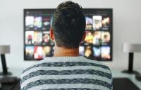 man watching a streamed performance on a TV or computer screen