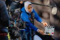 A young person operates a clapper board for filming