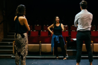 Female director giving feedback on a scene to two actors in a theatre by