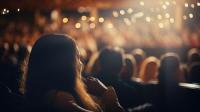 Audience in theatre. Image depicts backs of heads and stage in background