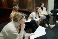 A group of people sitting on chairs reading a script