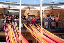 My Leeds 2023 Neighbourhood Hosts programme. People stood on a balcony waving and smiling.