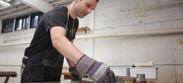 A man wearing gloves working with tools at a table