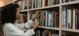 A woman looks through books on a library shelf