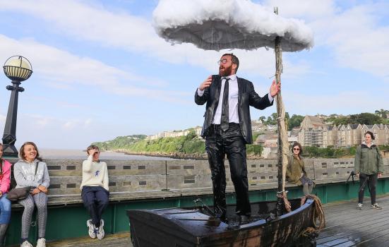 Performance shot: man in boat under a raining umbrella