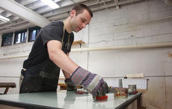 A man wearing gloves working with tools at a table