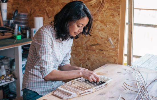 Woman weaving a chair seat inside workshop