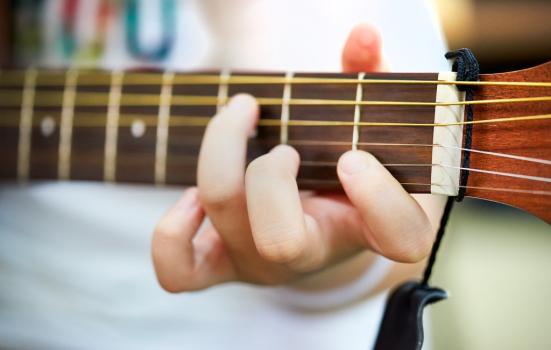 A close up of a person's hand playing the guitar