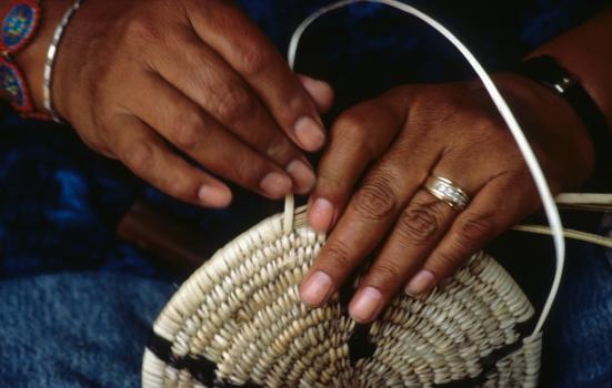 A close-up shot of a person's hands weaving a basket