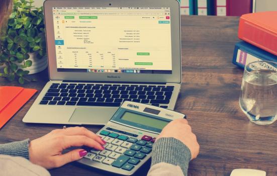 Photo of woman on laptop with calculator