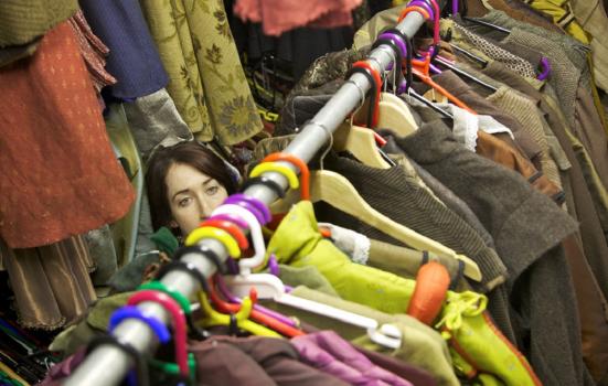 A woman standing behind a full clothes rail backstage at a production