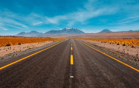 photo of a long straight road heading into the mountains behind