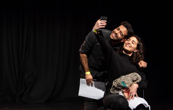 Two actors perform on stage, smiling taking a selfie