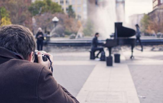 A photo of a man photographing a street piano player