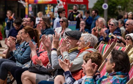 National Festival of Making 2022. People sat on folding wooden chairs smiling, laughing and clapping.