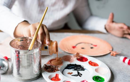 A child's hand pouring paint into a palette