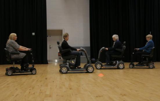 Photo of people rehearsing a dance in mobility scooters