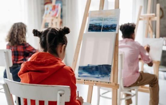 Young people painting on easels