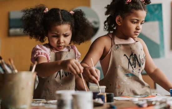 Two children standing at a table painting