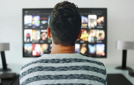 man watching a streamed performance on a TV or computer screen