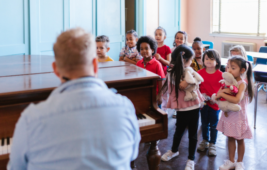 A music teacher playing piano for a class of children