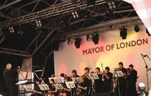 A big band standing on a stage playing their instruments with a conductor