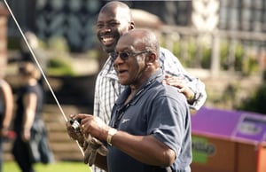 Two black men smiling holding a camera