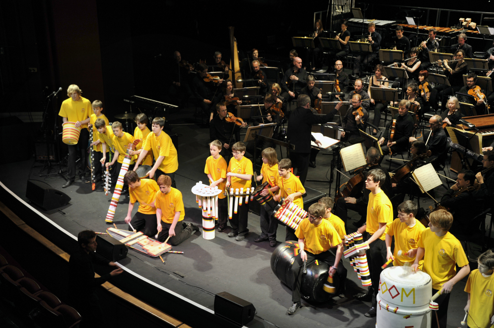 Young people in yellow t-shirts performing at a concert