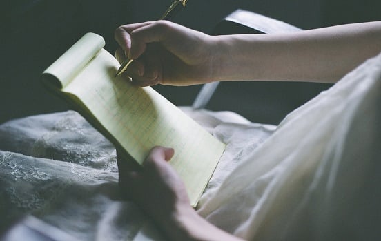 Photo of a person writing in a notebook