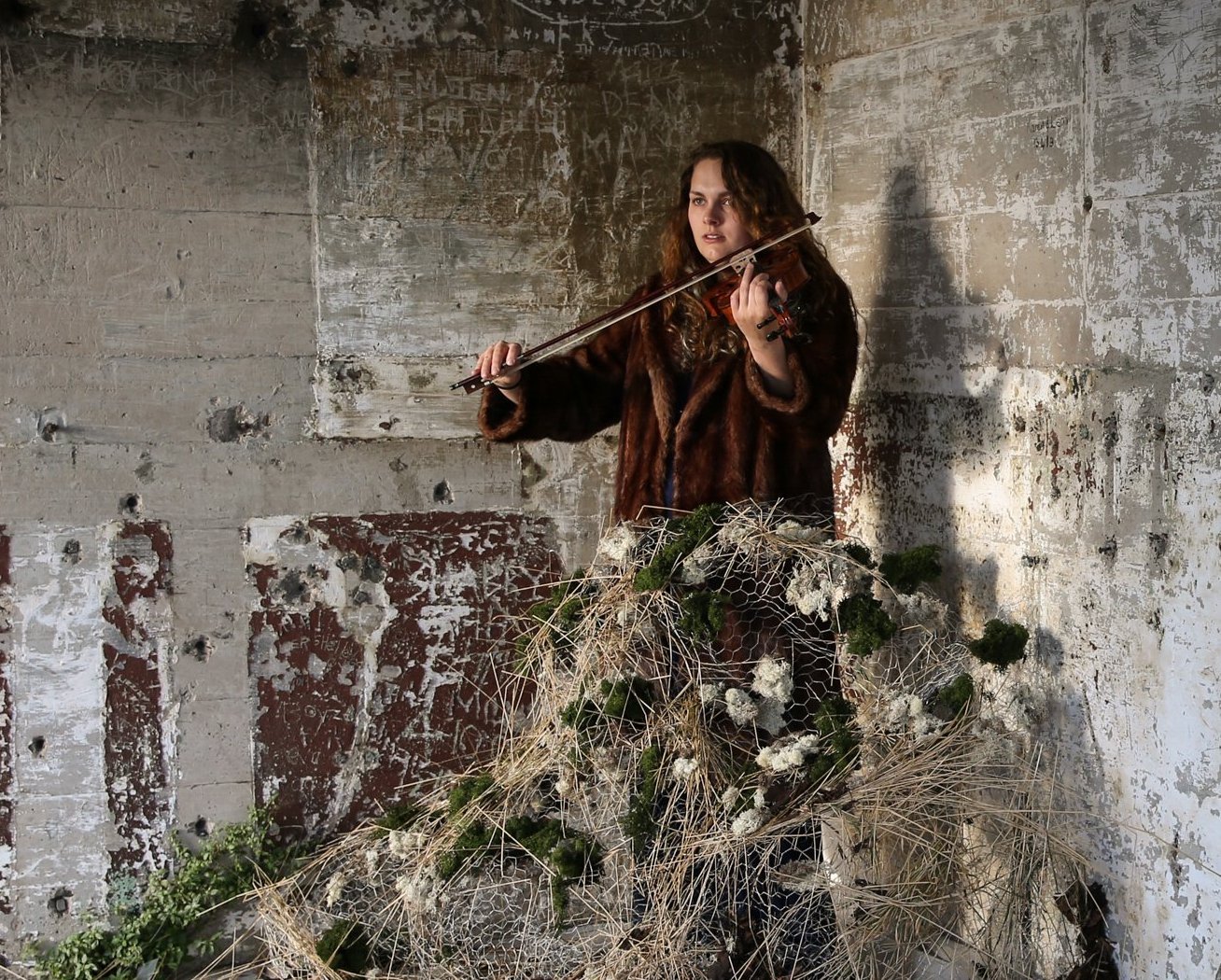 Photo of woman playing violin in concrete room