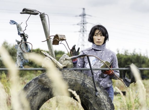 Woman standing behind fence with tyre