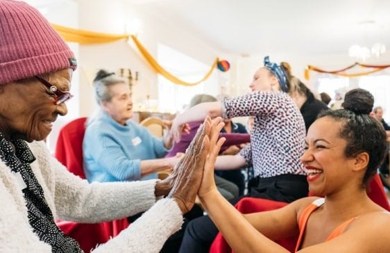 Photo of older woman and dancer clapping hands together