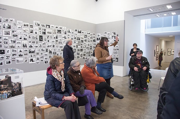 A gallery tour including people sitting down and a wheelchair user